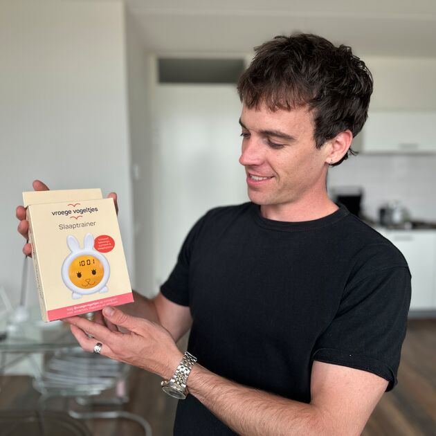 man met zwart shirt staat met product in zijn handen en kijkt naar het product
