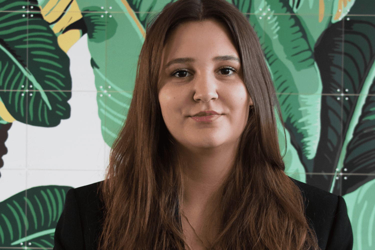 Een meisje kijkt in de camera, op de muur staat een tekening van een plant
