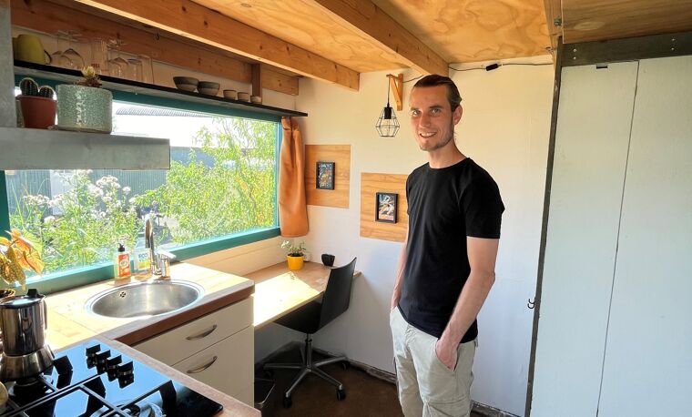 Man in zwart shirt staat in kleine keuken 