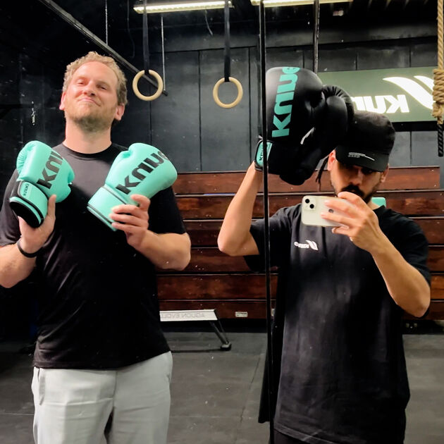 Twee mannen in sportzaal houden bokshandschoenen trots vast