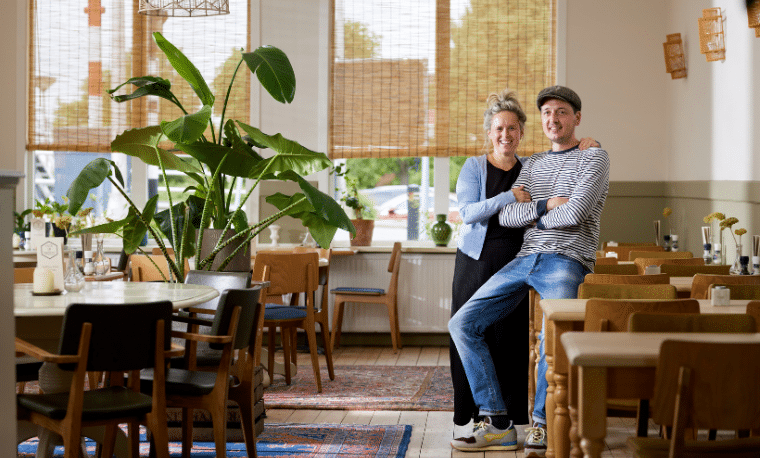 Man en vrouw zitten samen in een restaurant en lachen naar de camera