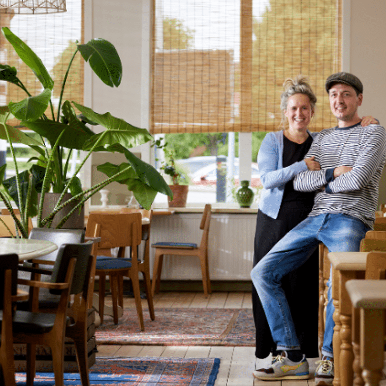 Man en vrouw zitten samen in een restaurant en lachen naar de camera