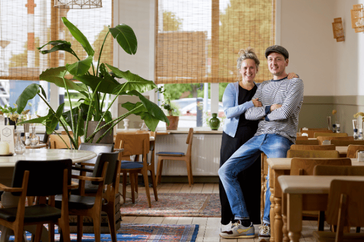 Man en vrouw zitten samen in een restaurant en lachen naar de camera