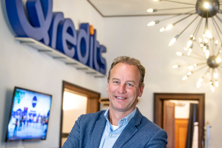 Man in blauw pak staat met zijn handen gevouwen