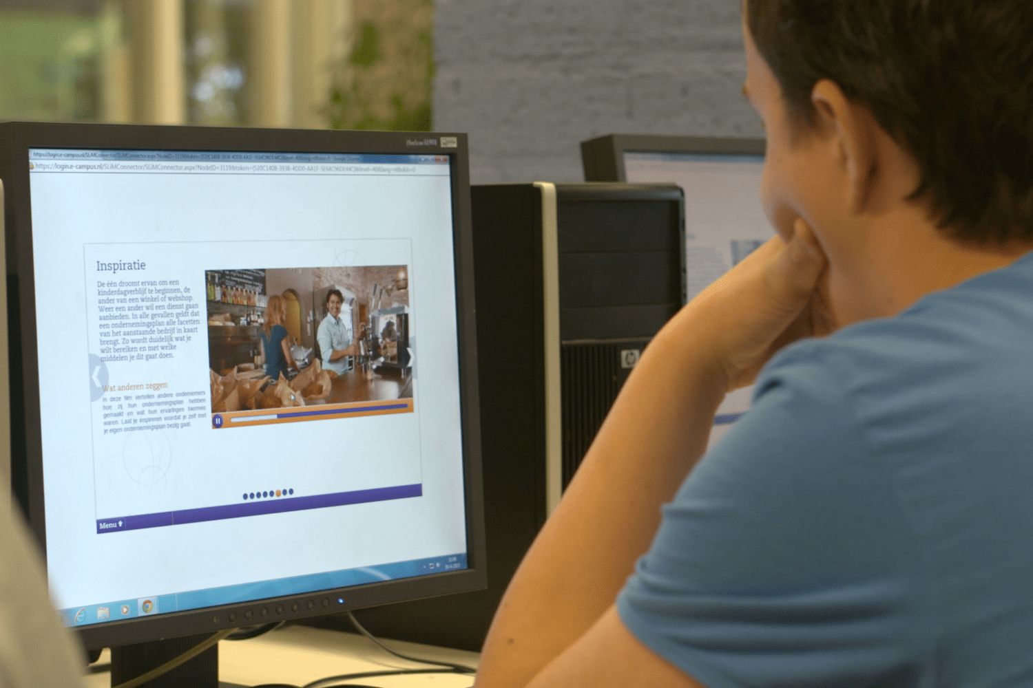 Man in blauw shirt zit achter computer met Qredits site open Man in blauw shirt zit achter computer met Qredits site open