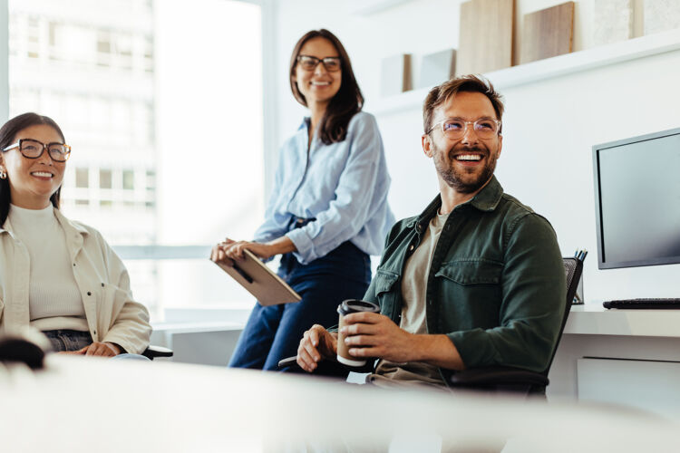 man-met-bril-en-koffie-lachend-met-twee-vrouwen