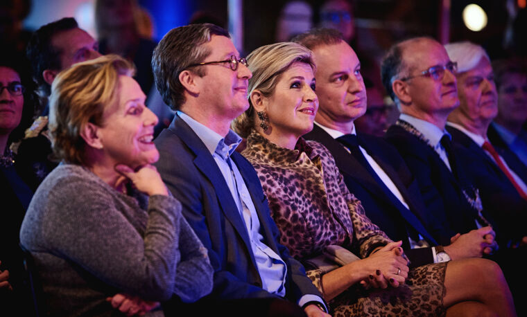 Koningin Maxima zit in een rij met mensen 