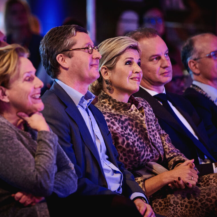 Koningin Maxima zit in een rij met mensen 