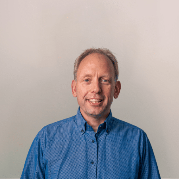 medewerker Qredits Peter Sanders man in blauw shirt voor grijze achtergrond