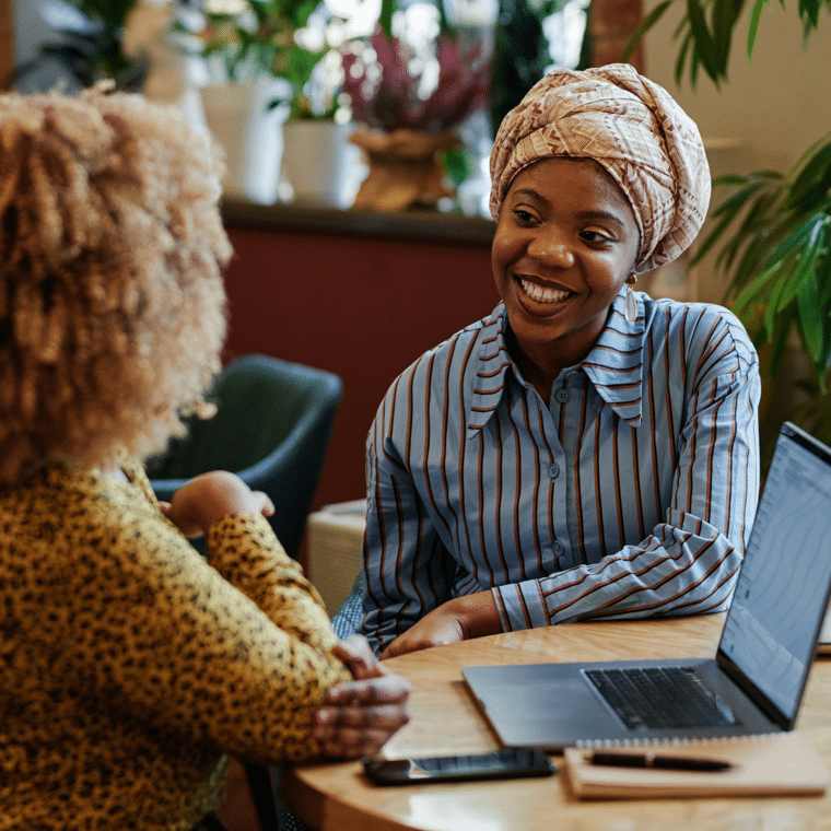 vrouw-met-hoofddoek-en-blauwe-blouse-en-vrouw-met-krullen-achter-laptop