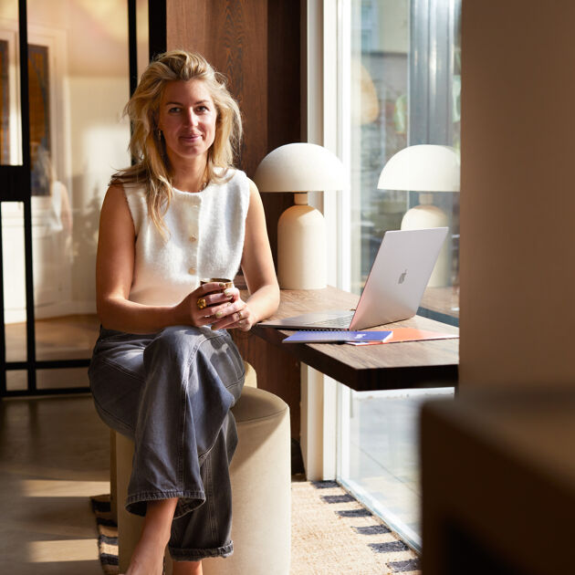 Lachende vrouw zit naast een laptop. 