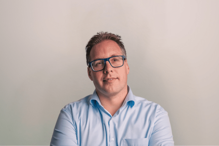 medewerker Qredits Daniel Wigger man in blauw shirt voor grijze achtergrond