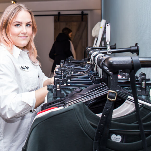 Vrouw staat voor een kledingrek met kleding 