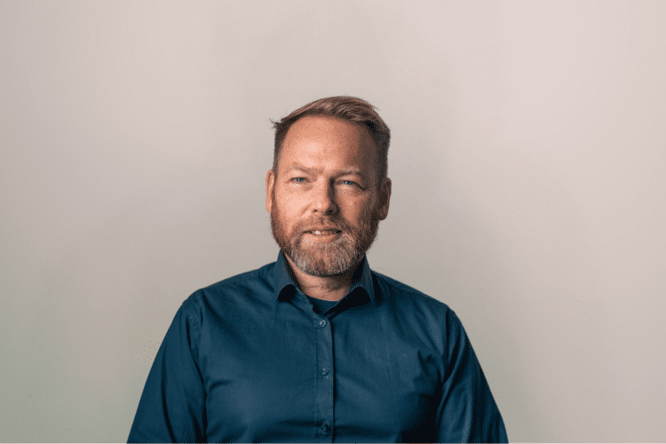 Errik medewerker Qredits man in blauw shirt voor grijze achtergrond
