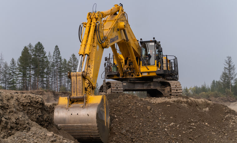 Gele graafmachine aan het werk bij donker zand
