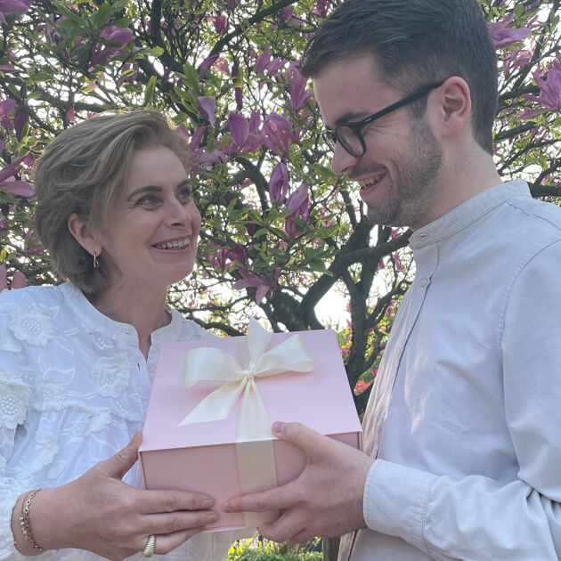 Man en vrouw hebben samen een roze doos met strik in de handen.