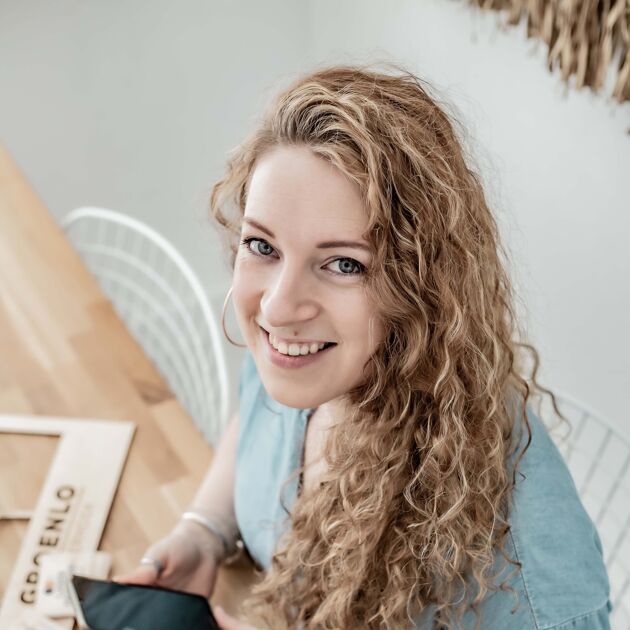 Vrouw met telefoon lacht naar camera
