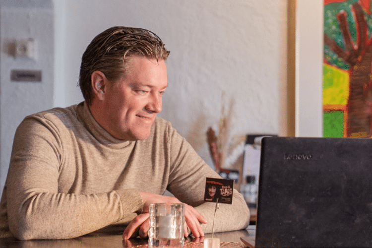 Man zit lachend achter zijn laptop