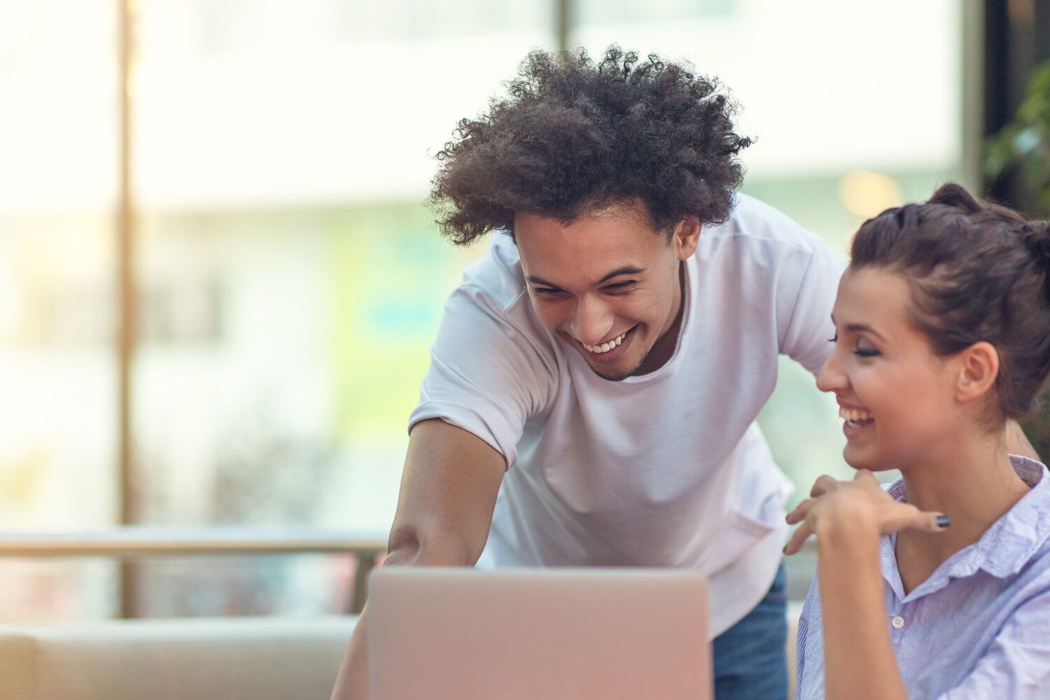 Man en vrouw lachen en kijken naar een laptop.