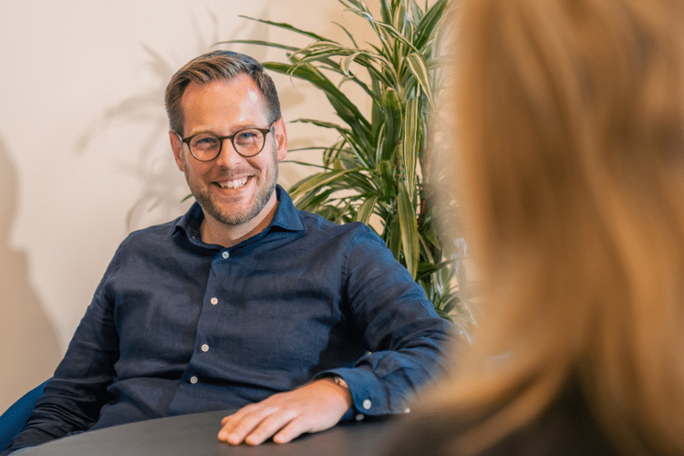 Man in blauw shirt met bril lacht naar vrouw