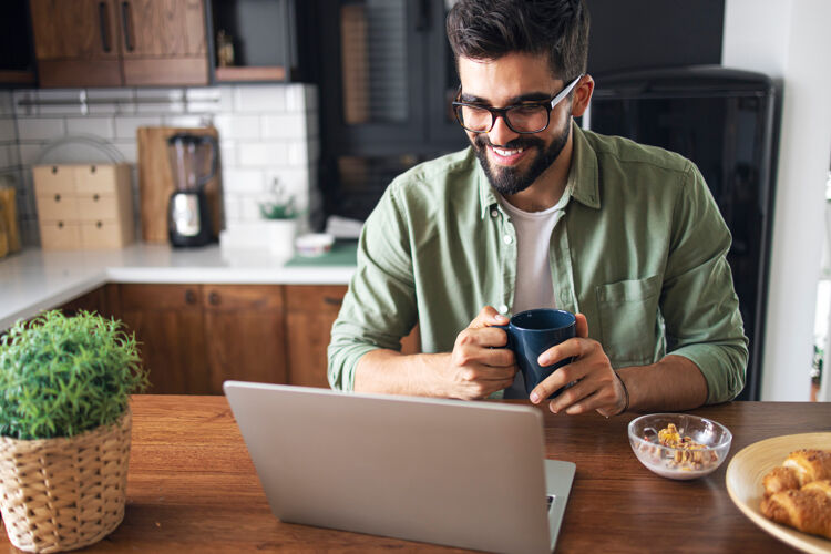 man-met-bril-zit-in-keuken-met-koffiemok