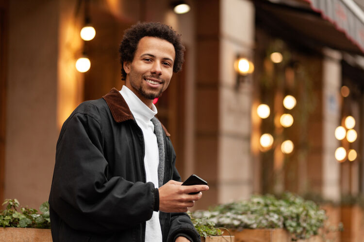 man-met-krullen-lacht-met-telefoon-in-hand