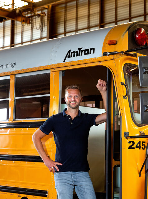 Man in zwart shirt zit op de voorkant van een gele schoolbus