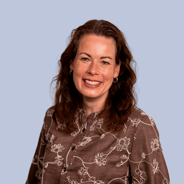 medewerker Qredits Mariëlle Voshaar vrouw in blauw shirt voor grijze achtergrond