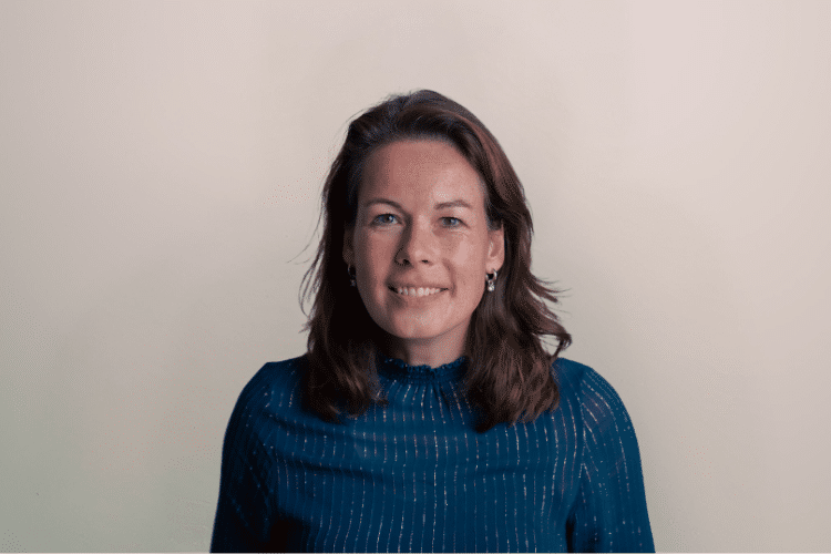 Marielle medewerker Qredits vrouw in blauw shirt voor grijze achtergrond