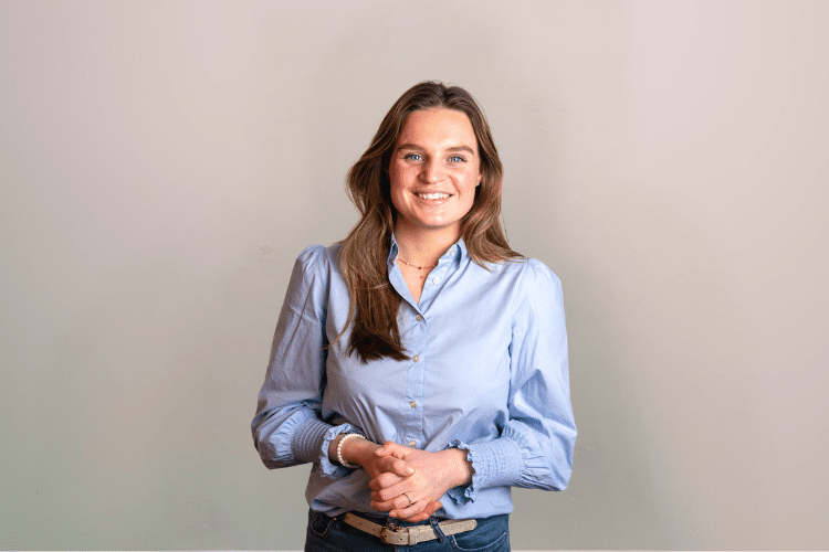 Isabel medewerker Qredits vrouw in blauwe blouse voor grijze achtergrond