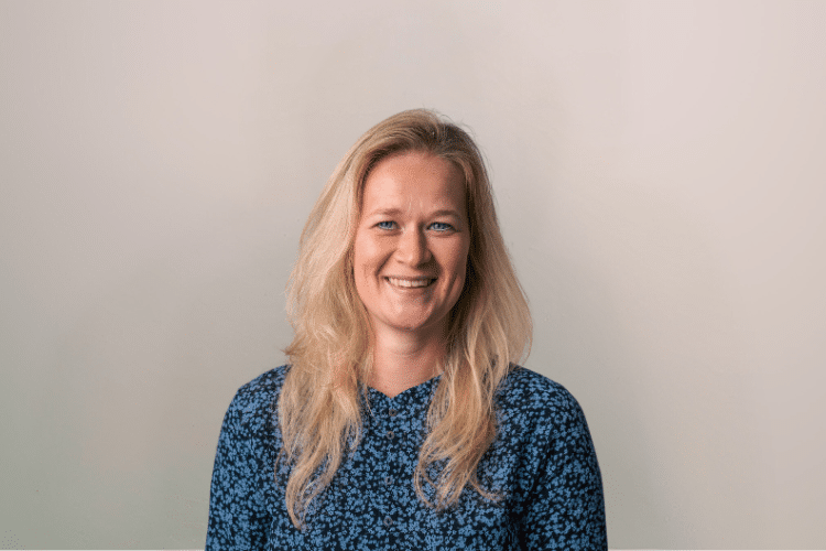 medewerker Qredits Rebekka Wassink vrouw in blauw shirt voor grijze achtergrond