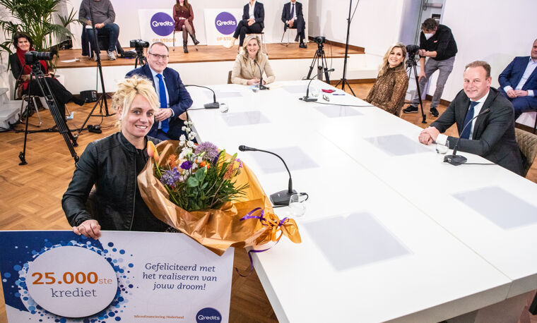 Groep mensen met vrouw met bloemen en grote kaart in perszaal 