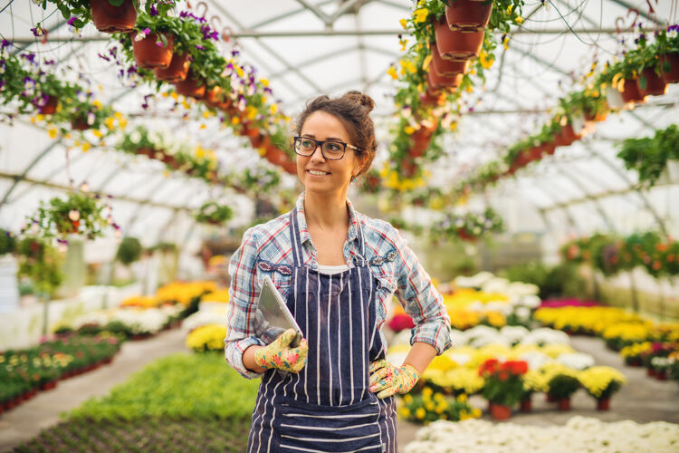 vrouw-staat-in-kas-met-bloemen-en-lacht