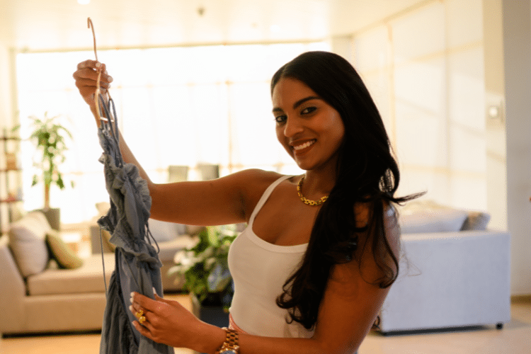 Vrouw in wit shirt en roze broek houd kleding vast