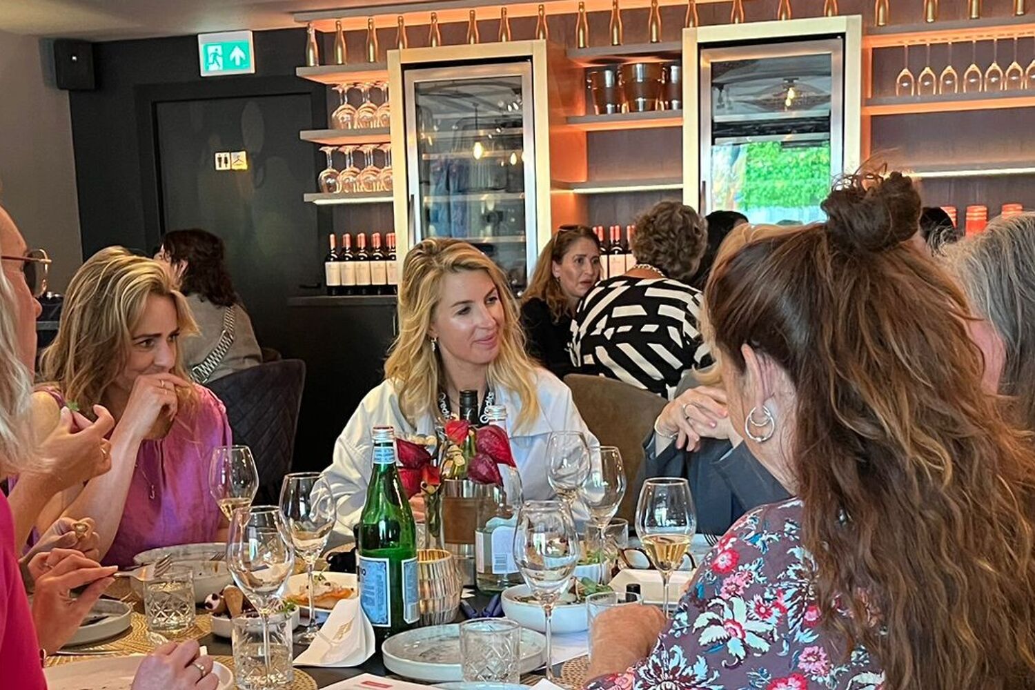 Vrouwen zitten pratend aan tafel tijdens een diner. 