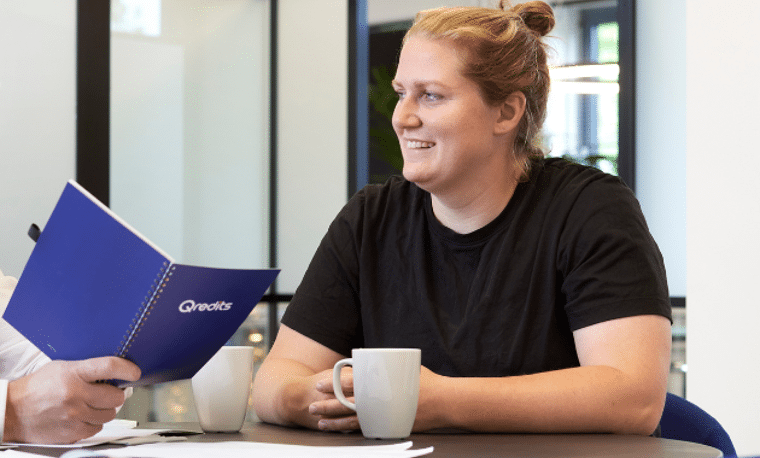 Vrouw in zwart shirt luistert naar Qredits medewerker aan tafel