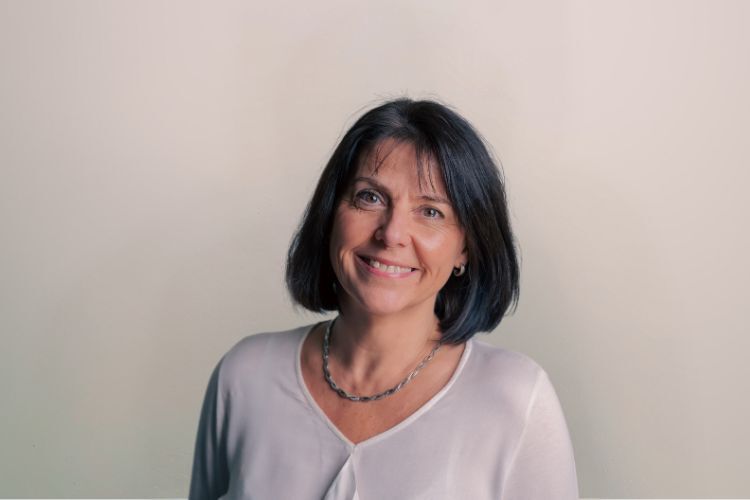 Evelyne medewerker Qredits vrouw in wit shirt voor grijze achtergrond
