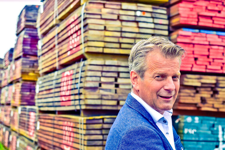 Man in blauw pak voor een pallet met planken