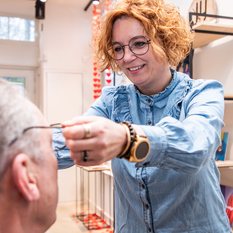Vrouw helpt man met uitzoeken bril