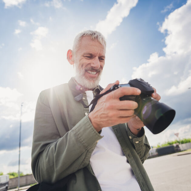 man kijkt naar camera met blauwe lucht op de achtergrond 