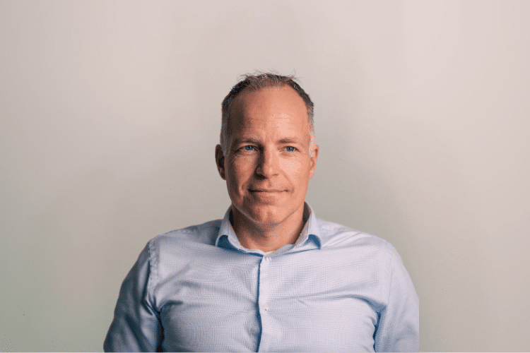 Edwin medewerker Qredits man in blauw shirt voor grijze achtergrond