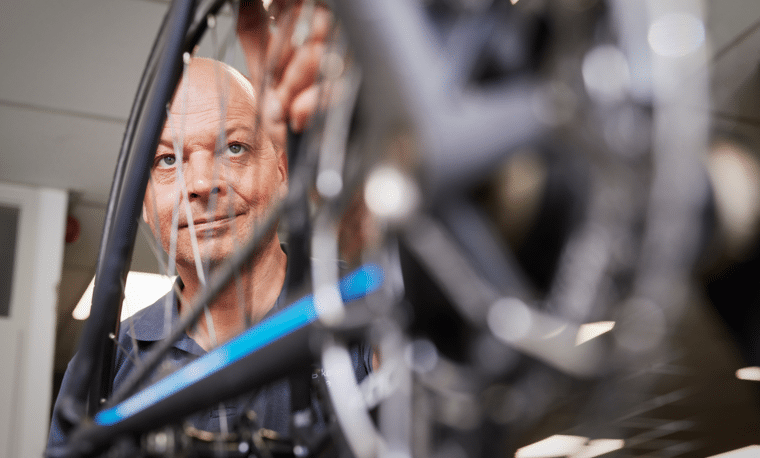 Man in blauw shirt kijkt naar zijn fiets