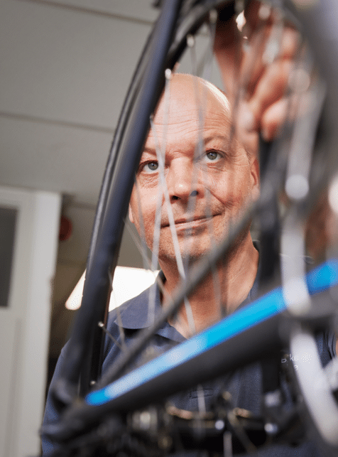 Man in blauw shirt kijkt naar zijn fiets
