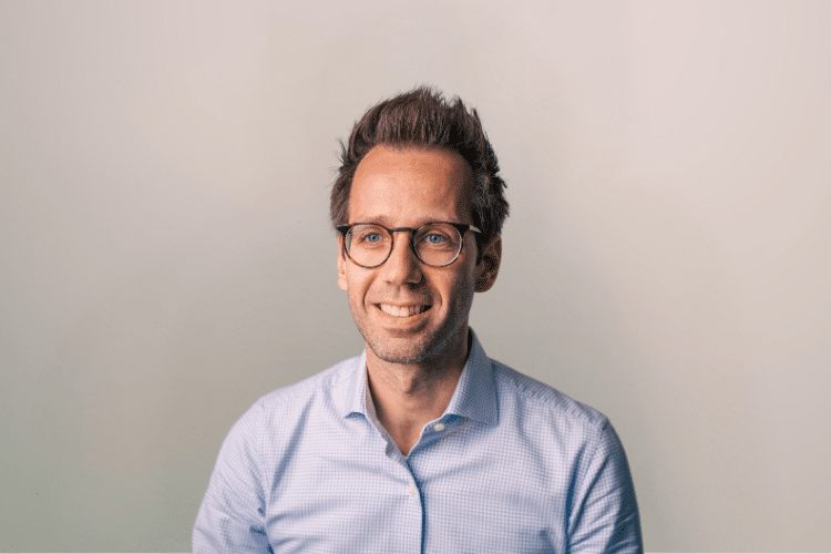 Bart medewerker Qredits man in blauw shirt voor grijze achtergrond