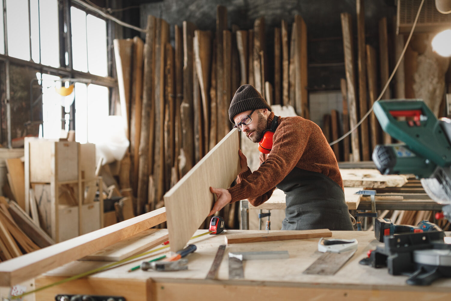 Man met houtenplaat Man bekijkt een houten plaat in houtbewerking ruimte