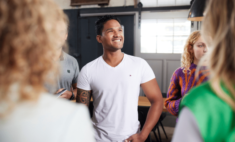 Man in wit shirt lacht met mensen om zich heen
