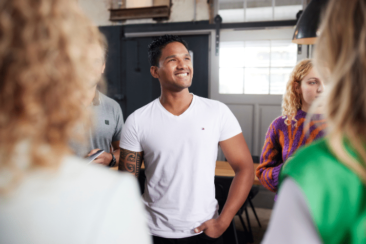Man in wit shirt lacht met mensen om zich heen