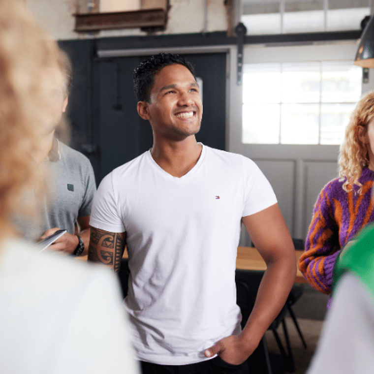 Man in wit shirt lacht met mensen om zich heen