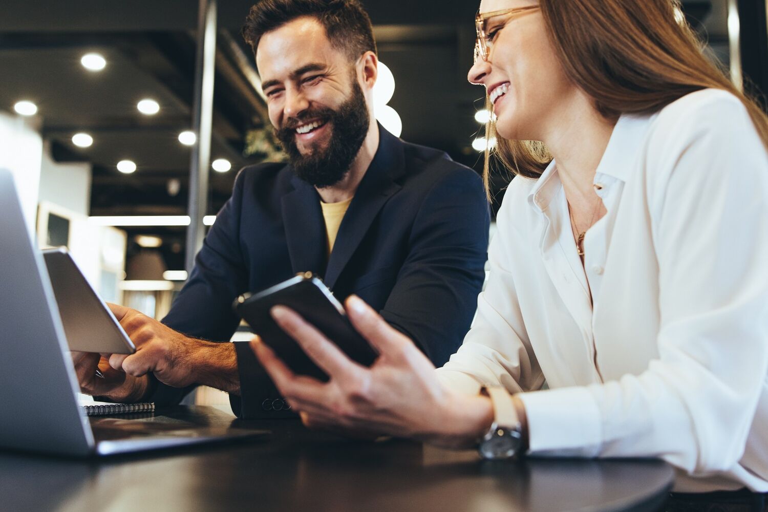 Man en vrouw zitten en kijken lachend naar een laptop.