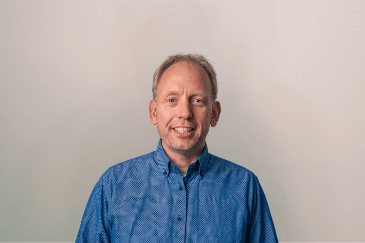 Peter medewerker Qredits man in blauw shirt voor grijze achtergrond